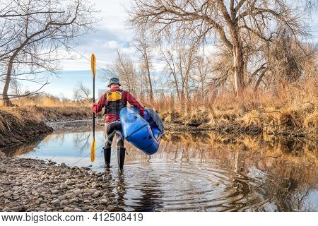 senior male paddler is launching his inflatable packraft on a river in early spring spring - Poudre River in northern Colorado