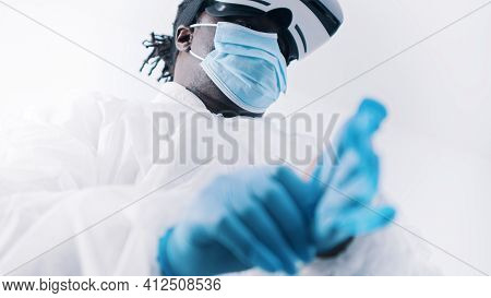African American Black Doctor In Protective Uniform And With Vr Glasses Putting On Gloves. High Qual