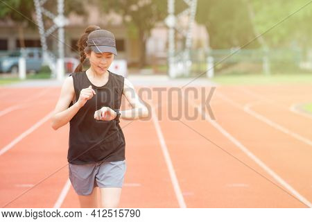 Portrait Of Young Athlete Runner Woman Running In The Running Track And She Looking To Her Smart Wat