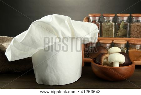 Sammansättning med kockens hatt och kitchenwear på bordet på grå bakgrund
