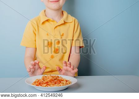 Cute Boy Eating Spaghetti Bolognese At Home. Concept Of Dirty Stains On Clothes. Isolated On Blue Ba