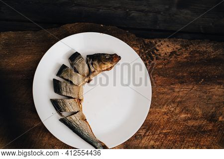Sliced Dried Fish On A White Plate On A Wooden Table