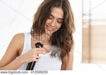 Pretty Young Lady Spraying Hairspray Styling Wavy Hair Indoor
