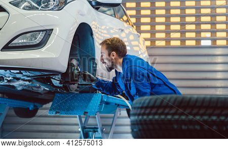 Car mechanic changing tire in his workshop