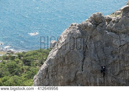 High Cliff And Small Figure Of Rock Climber. Sea Is Behind. Extreme Sport. Spring, Cremea, Breathtak