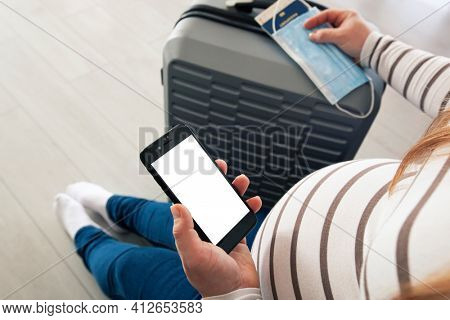 The pregnant woman holding the mobile phone with blank screen as a mockup for digital vaccination certificate 