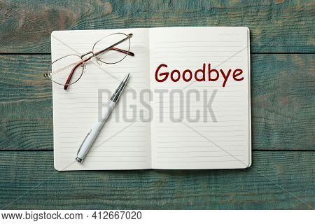 Notebook With Word Goodbye On Wooden Table, Top View