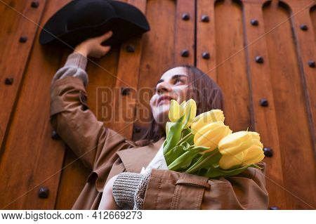 Beautiful Young Girl In A Hat With A Big Bouquet Of Yellow Tulips. Walks Around The Old Town In Euro