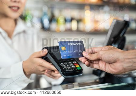 Close Up Shot Of Customer Hand Using Dummy Credit Card For Payment To Waitress At Cashier In Cafe Re