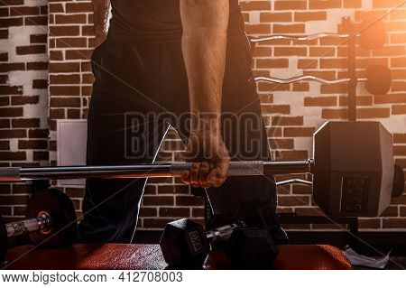 Female Personal Trainer Helping A Young Man Lift Dumbells While Working Out In A Gym