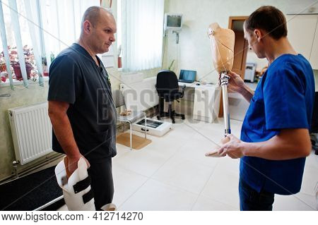 Two Prosthetist Man Workers With Prosthetic Leg Working In Laboratory.
