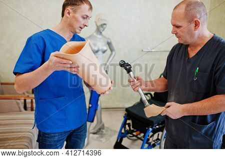Two Prosthetist Man Workers With Prosthetic Leg Working In Laboratory.