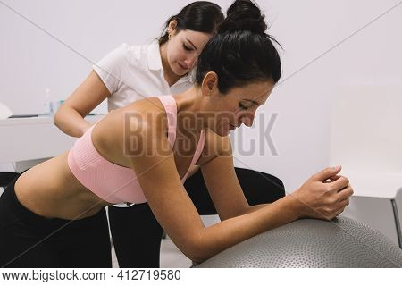 Woman Patient Leaning On A Fit Ball Is Helped By A Physiotherapist On A Hypopressive Abdominal Exerc
