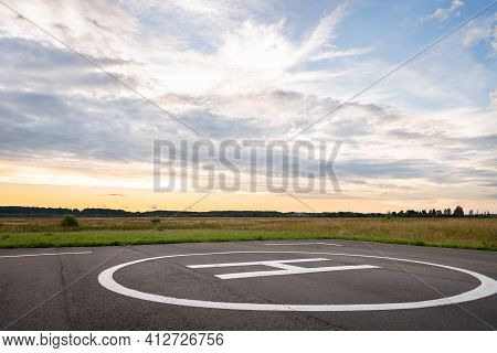 View Of The Private Helipad On A Warm Summer Evening. An Asphalt Helipad Against The Backdrop Of A G