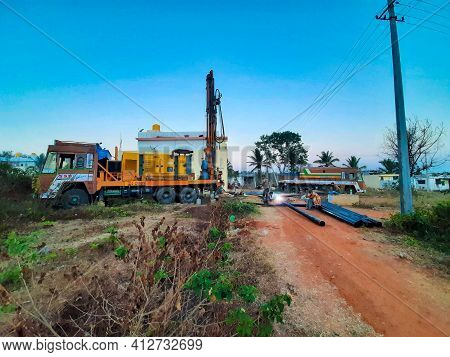 Closeup Of Borewell Drilling Lorry Or Vehicles With Tools, Pipe, Machine And Working Labour And Puja