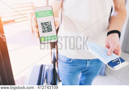 The man holding the mobile phone with empty space as a mockup for digital vaccination certificate in one hand and passport, mask and ticket in another one