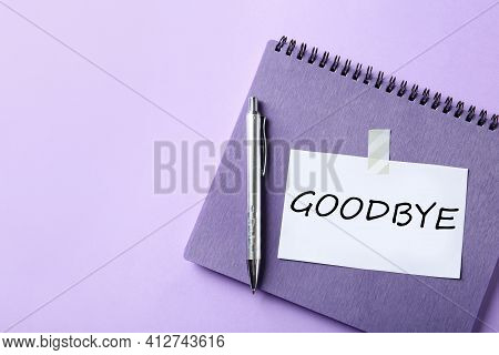Note With Word Goodbye, Notebook And Pen On Violet Background, Space For Text