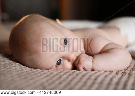 Fair-haired Child Is Lying On The Bed At Home With A Thoughtful Look Out The Window. Keeps A Finge I