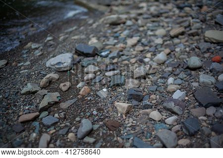 Pebbles And Colored Pebbles In Water Close-up. Texture Of Mixed Different Sizes Stones On The Shore 