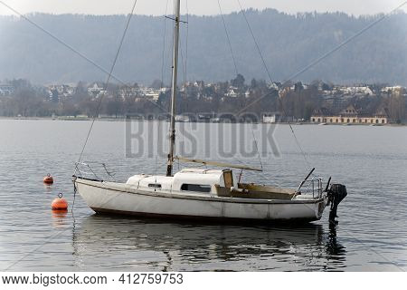 Old Interesting Boat With Black Outboard Motor Floats Leaderless On The Water, The Anchor Was Laid