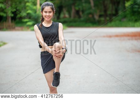 Portrait Of Runner Woman Holding Her Knee, Doing Stretching And Warming Up Her Body Before Running. 