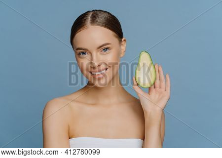 Natural Skin Care Concept. Beautiful Brunette Young Woman Holds Half Of Avocado Enjoys Organic Cosme