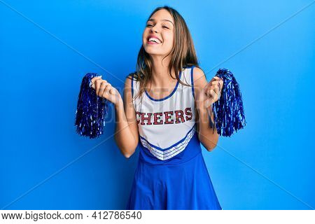 Young brunette woman wearing cheerleader uniform smiling and laughing hard out loud because funny crazy joke. 
