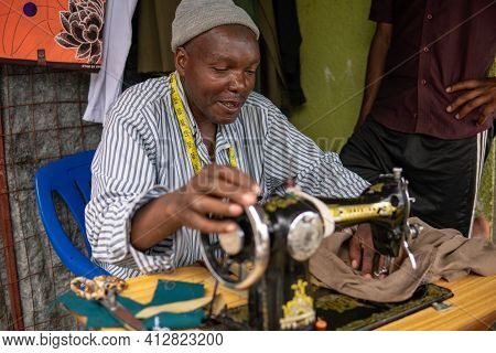 Tanzania, Masai Village - January 2020: Portrait Of Sewer Of Swiss Tailor Maasai Man Working With Se