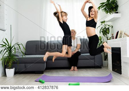 Adult Woman With Her Granddaughters. Morning Exercises, Yoga - Do At Home All Together. Grandmother 
