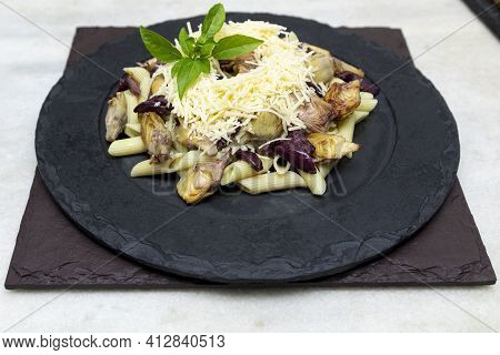 Pasta With Black Olives, Parmesan Cheese, Artichoke Hearts, Topped With Fresh Basil Leaves.
