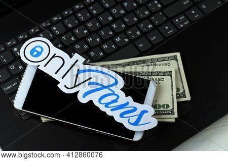 Kharkov, Ukraine - February 14, 2021: Onlyfans Paper Logo With Smartphone And Dollar Bills On Black 
