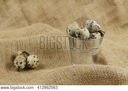 Quail Eggs And A Metal Bucket On Sacking. Raw Eggs And A Small Galvanized Bucket. Close-up, Selectiv