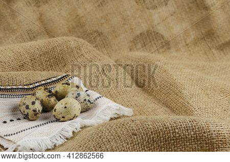 Quail Eggs And Ethnic Napkin On Sacking. Raw Eggs And A White Fringed Napkin. Close-up, Selective Fo