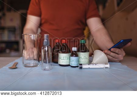 A Middle Aged Man Reading Receipt From Mobile Phone And Doing Hand Sanitizer At Home