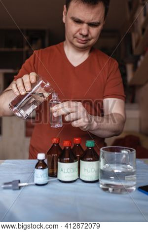A Middle Aged Man Reading Receipt From Mobile Phone And Doing Hand Sanitizer At Home
