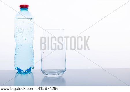 Mineral Water Bottle And Glass On A White Background. Mineral Water With Gas. Front View.