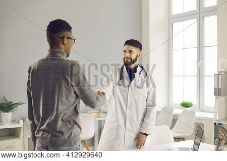 Smiling Man Doctor Therapist Shaking Hand To Black Man Patient After Successful Checkup