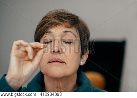 Portrait Senior Woman Taking A Auto Test For Covid-19 At Home With Antigen Kit. Introducing Nasal Sw