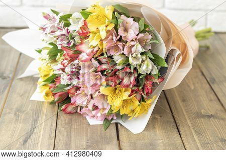 Bouquet From Multi-colored Flowers On The Wooden Background. Multicolored Alstroemerias, Pink, Yello
