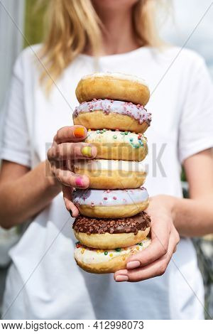 Say No To Junk Food. Cropped Shot Of A Woman Holding A Stack Of Different Sweet Colorful Glazed Donu