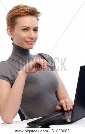 Smiling young businesswoman working on laptop computer.