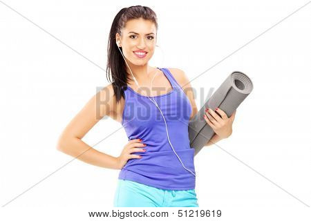Female athlete listening music and holding a mat, isolated against white background