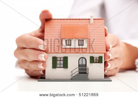 pisture of man and woman hands holding paper house
