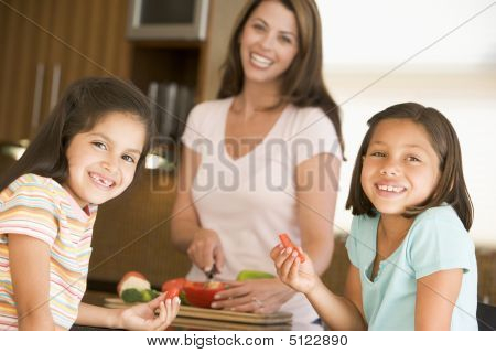 หญิงที่รับประทานพริกไทยแถบในขณะที่แม่กำลังเตรียมอาหาร Mealtime