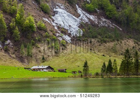 Farm house on mountain lake Obersee lake in spring. Bavaria, Germany
