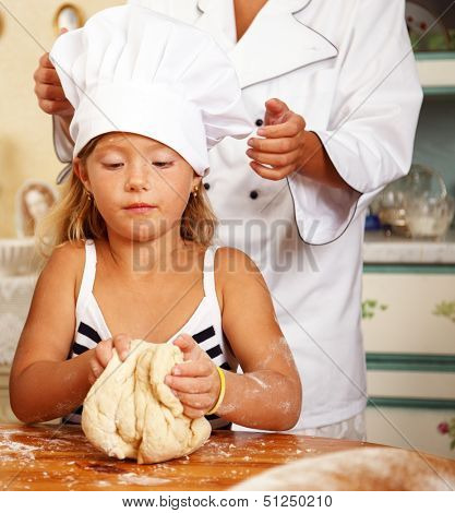 Cook helping her little protege cooking homemade pastry