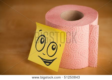 Drawn smiley face on a post-it note sticked on a toilet paper