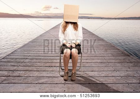 woman sitting on a wharf with a box in her face