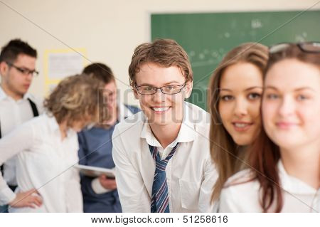 Smiling high school students posing in a schoolroom