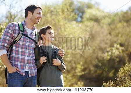 Father And Son Hiking In Countryside Wearing Backpacks
